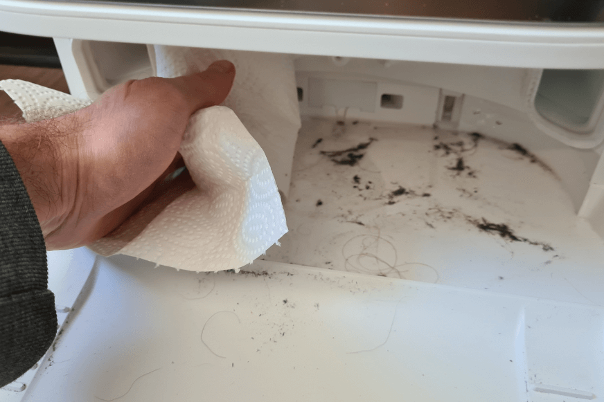 Der Dreck in der Reinigungswanne der Basisstation des Dreame L10s Ultra wird mit einem Wischtuch beseitigt.